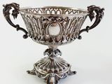 a silver bowl that is on a stand on a white background
