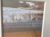 framed photograph of a painting of a landscape in a white frame on a wall