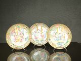 trois assiettes chinoises ornées de motifs, posées sur une table