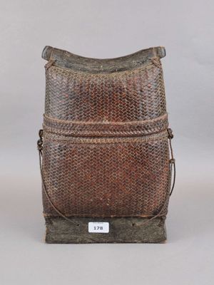 une photo représentant un sac tissé marron posé sur un support en bois