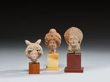 un ensemble de quatre sculptures représentant des têtes, montées sur des socles en bois
