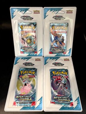 trois paquets de cartes à collectionner Pokémon dans des pochettes en plastique, posés sur une table