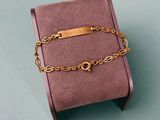 gold plated bracelet on a pink box on a green surface