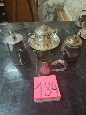 un bout de papier rose posé sur une table, à côté d'une théière en argent