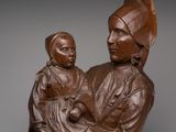 a statue of a woman holding a child on top of a wooden base