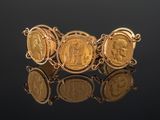 a close up of a bracelet with gold coins on a black surface