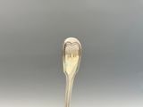 une cuillère en argent avec un manche en forme de cœur, posée sur une table