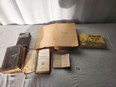several old books are sitting on a table next to a white curtain