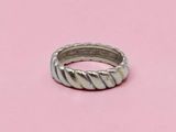 un gros plan d'une bague en argent posée sur une surface rose