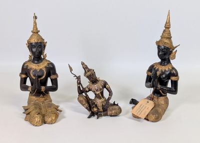 trois statues en bronze représentant une femme et un homme assis sur un rocher
