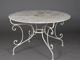 une table en fer forgé blanc avec un plateau circulaire sur fond gris