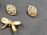 three pieces of gold jewelry on a table with a bow