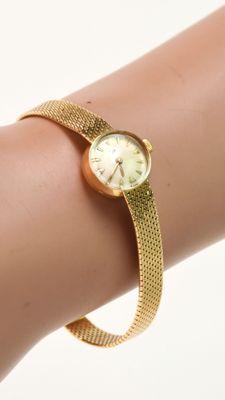 le poignet d'une femme, sur lequel se trouve une montre en or