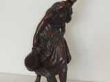 une statue représentant une femme tenant un sac sur une étagère