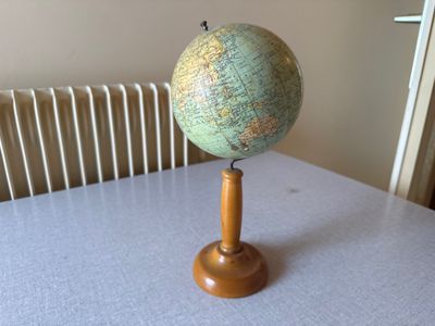 un petit globe posé sur un socle en bois, sur une table