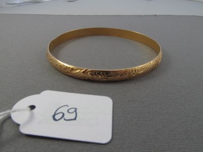un bracelet en or muni d'une plaque, posé sur une table