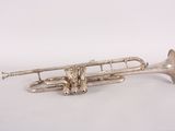 an old silver trumpet sitting on top of a white surface