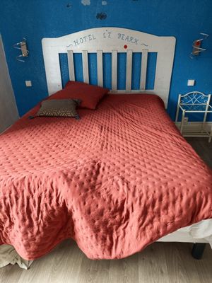 a bed with a red comforter and a white headboard