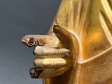 a gold statue of a person holding a cigarette in his hand