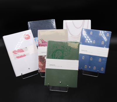 five notebooks with different designs on them on a black surface