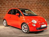 a small red car parked in front of a brick wall