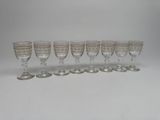 six wine glasses lined up in a row on a white surface