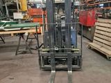 a forklift in a warehouse with pallets of wood