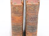 two old books sitting on top of each other on a white surface