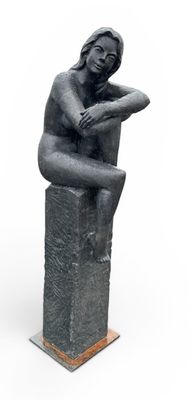 statue d'une femme assise sur un bloc, les mains posées sur les genoux