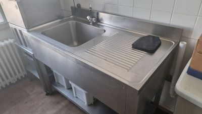 un évier en acier inoxydable dans une cuisine, à côté d'un radiateur