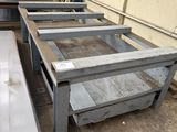 several metal tables and benches in a warehouse with a wall in the background