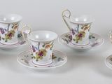 six tasses et soucoupes ornées de fleurs, posées sur une table