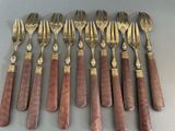 six forks and six spoons are lined up on a table