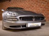 a maserat parked in a garage with a brick wall in the background