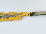an image of a knife with a gold handle on a white surface