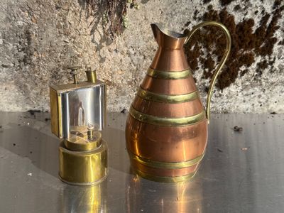 un petit pichet en cuivre à côté d'un petit récipient en métal