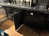 un plan de travail noir sur lequel sont posés des verres à vin et des bouteilles