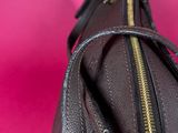 a close up of a black purse on a pink surface