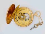 a gold pocket watch with a key and a keychain