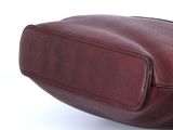 maroon leather purse on a white surface with a white background