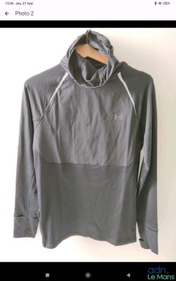 Le t-shirt est gris et comporte une capuche.