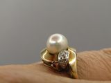 a pearl and diamond ring on a person ' s finger