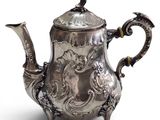 an antique silver tea pot with a bird on top