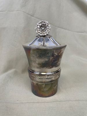 un récipient en argent surmonté d'une fleur