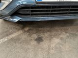 the front bumper of a blue car with a number plate on it