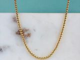 un collier de perles dorées posé sur un comptoir en marbre