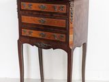 a small wooden chest of drawers on a stand