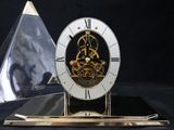 a clock that is sitting on a table next to a pyramid