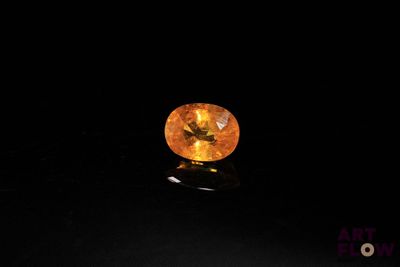 a yellow sapphire stone on a black surface