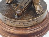 bronze statue of a child holding a book on a wooden base